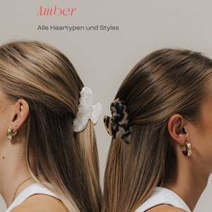 Zwei Frauen von hinten mit langen, glatten Haaren, die mit großen Haarklammern im Half-up-Hairstyle gestylt sind – links eine weiße, rechts eine schwarz-beige gemusterte Klammer. Darüber der Schriftzug ‚Amber – Alle Haartypen und Styles‘.