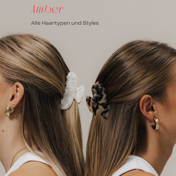 Zwei Frauen von hinten mit langen, glatten Haaren, die mit großen Haarklammern im Half-up-Hairstyle gestylt sind – links eine weiße, rechts eine schwarz-beige gemusterte Klammer. Darüber der Schriftzug ‚Amber – Alle Haartypen und Styles‘.