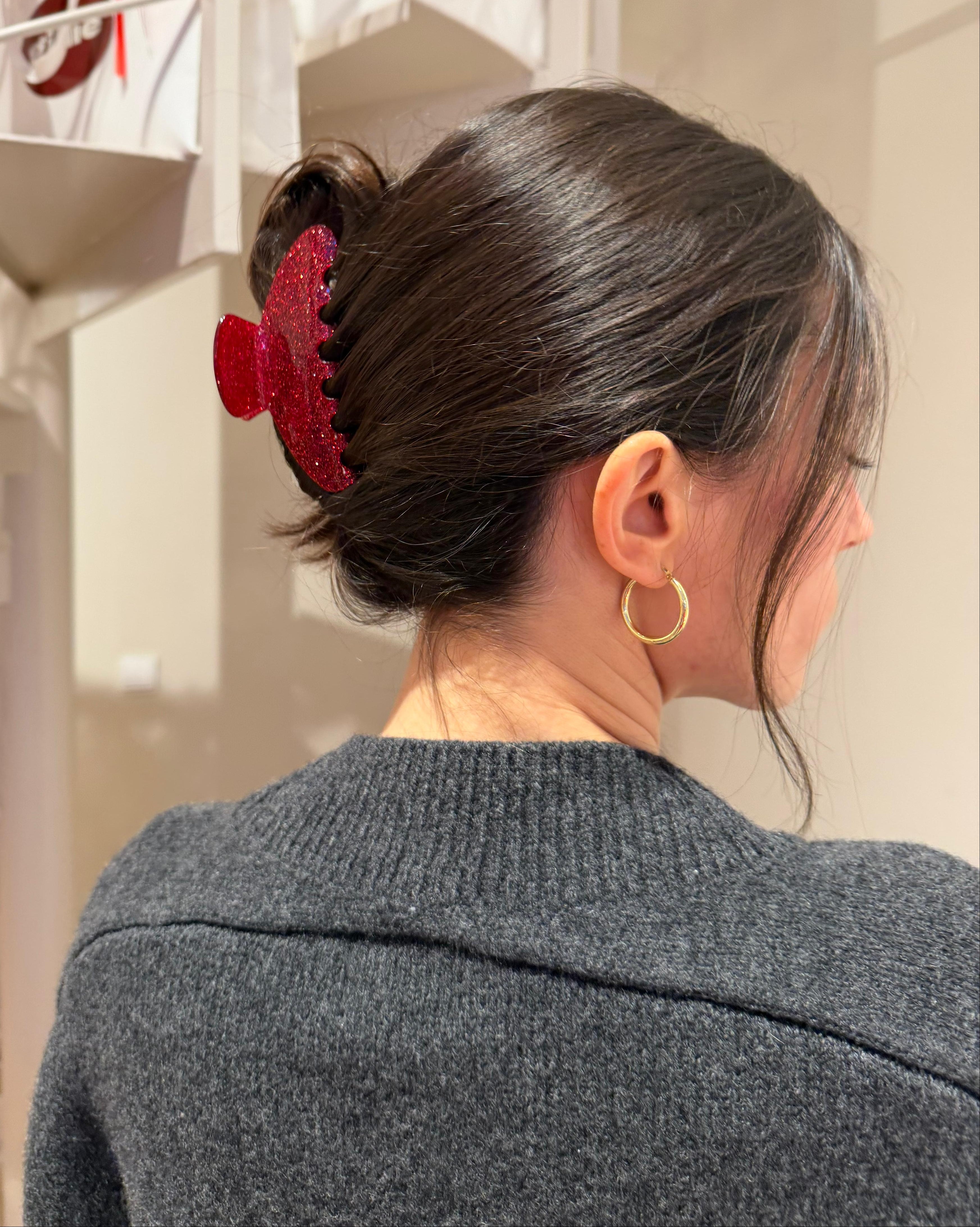 Rote glitzernde gillie Haarklammer im hochgesteckten dunklen Haar, getragen von hinten, eleganter Look in weihnachtlicher Umgebung.