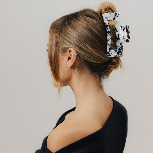 Frau mit Half-Bun, gestylt mit unserer schwarz-weiß gemusterten Haarklammer – sicherer Halt trifft auf cooles Design.