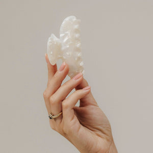 Unsere Haarklammer in Shell (8,5 cm) aus Bio-Acetat – stilvoll in der Hand präsentiert, Fokus auf die strukturierte Oberfläche.