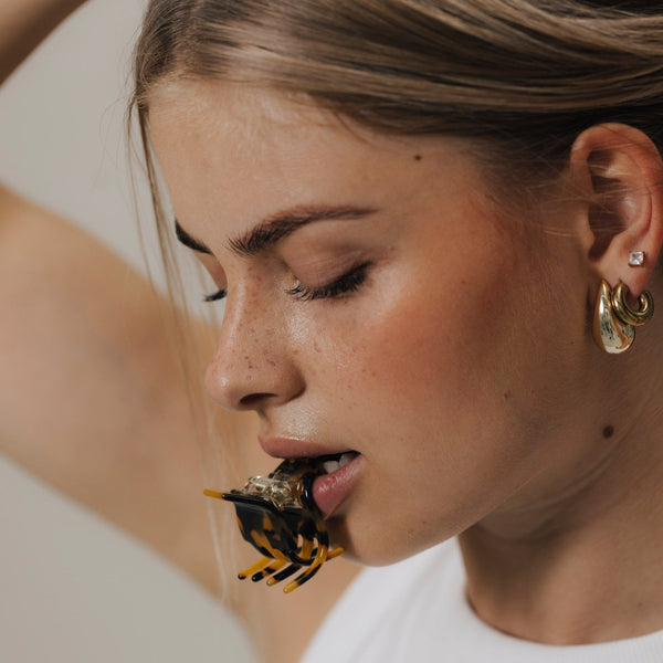 Nahaufnahme: Frau beißt spielerisch in unsere kleine Haarklammer in Tortoise-Optik – ein edgy und ästhetisches Detailbild.