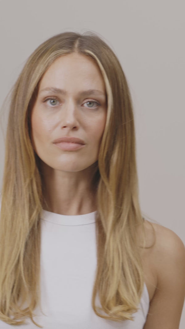 Frau mit blonden Haaren, die sich ihre Haare zu einem Dutt bindet mit unserem beigen Maulbeerseidenscrunchie.