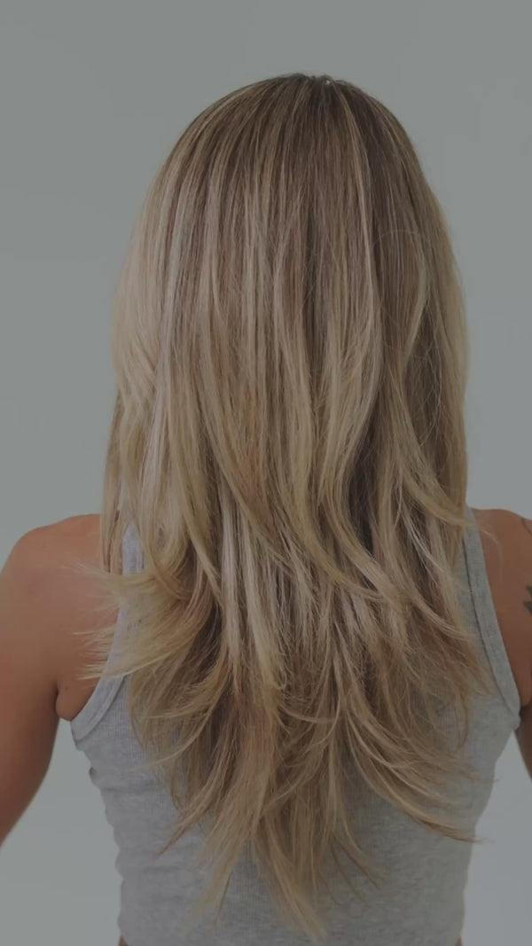 Frau mit blonden Haaren wird von der Seite gefilmt, während sie sich die Haare zu Half Bun mit tortoise-farbener Haarklammer stylt.